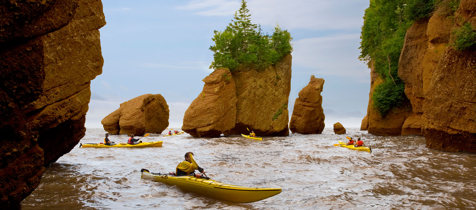 Un groupe de personnes dans des kayaks jaunes pagayant à Hopewell Rocks.