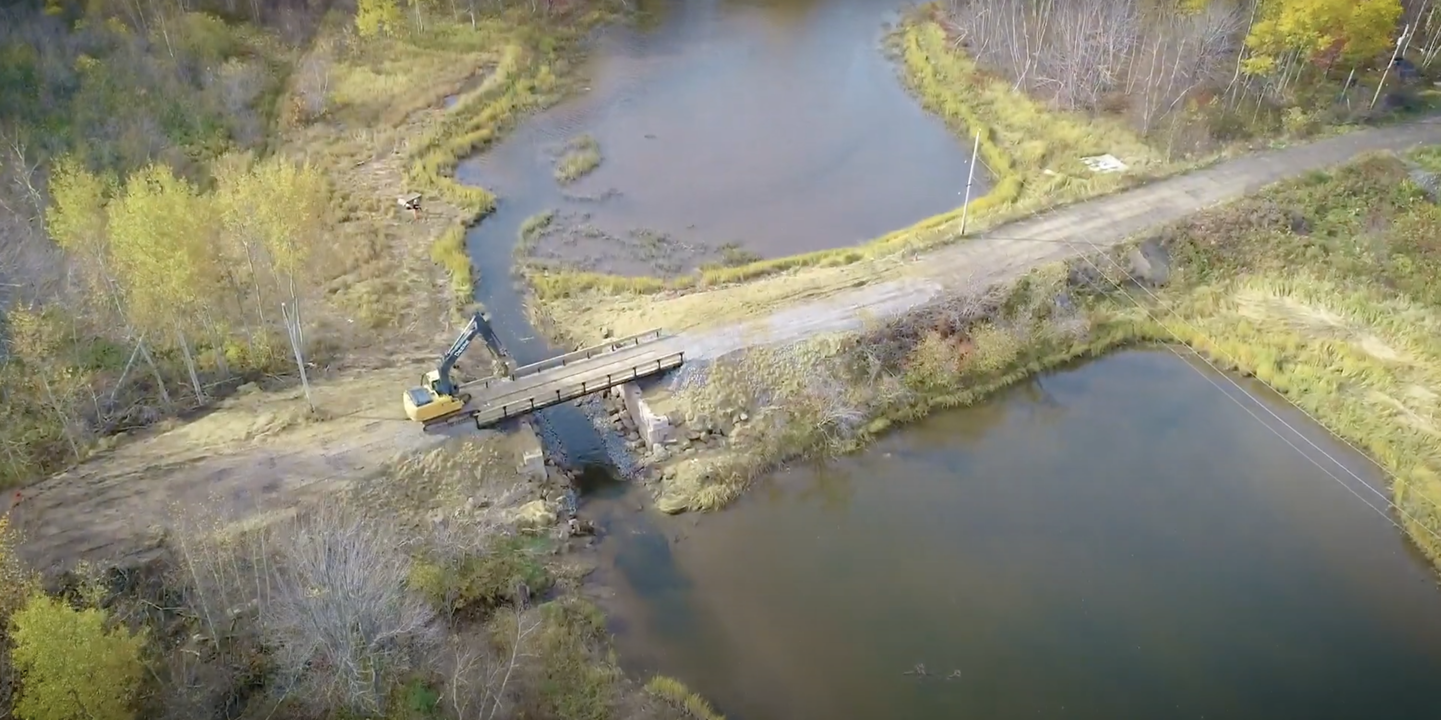 Vue aérienne d'une rivière. Un pont terrestre traverse la majeure partie de la rivière, mais il y a une petite ouverture sur le côté gauche où l'eau continue, avec un pont qui traverse cette brèche. 