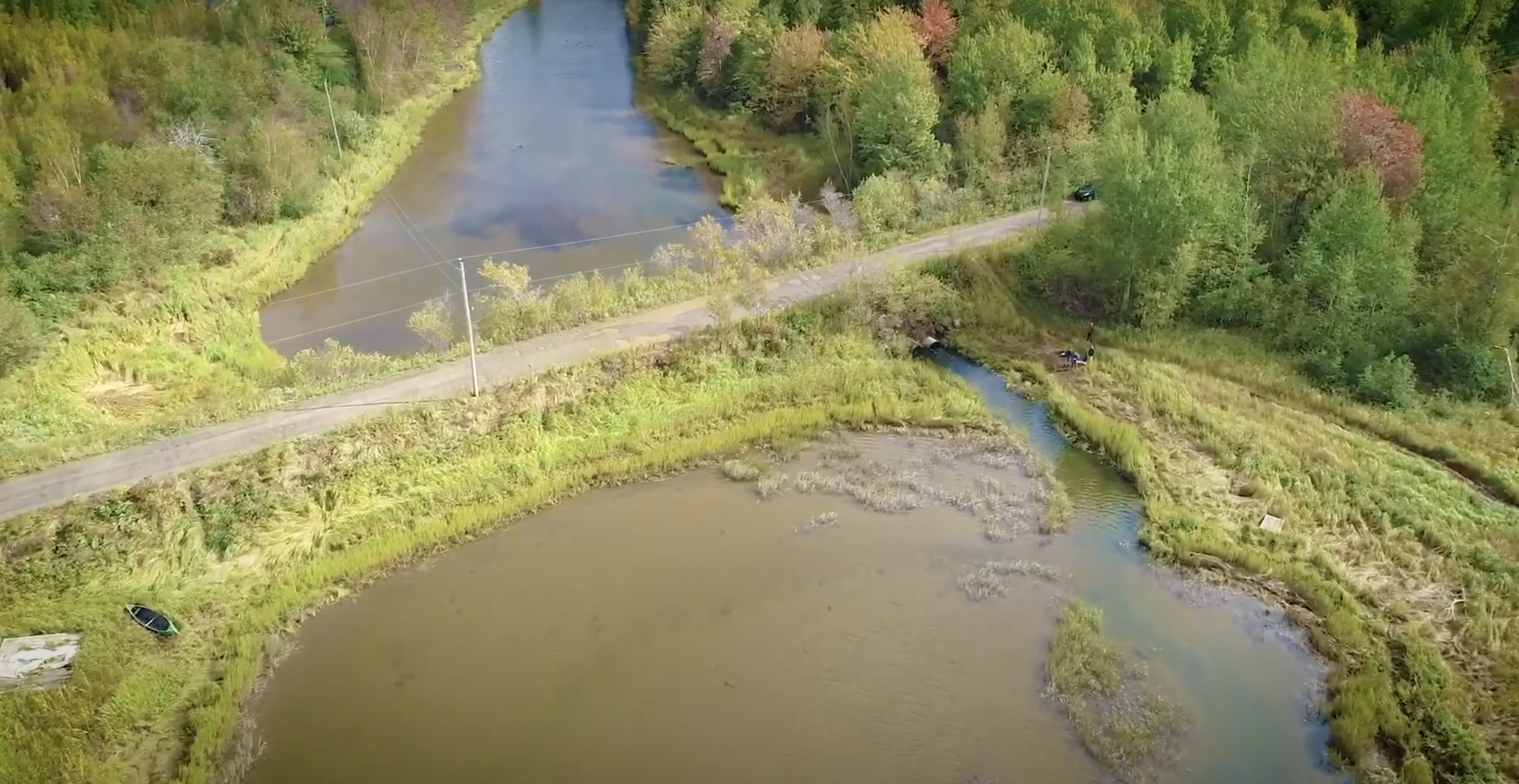 Vue aérienne d'une rivière. Un pont terrestre traverse la rivière, obstruant l'écoulement de l'eau de part et d'autre. 