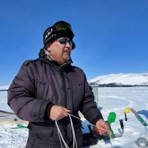 Rex Holwell outdoors on a sunny day, performing data collection for ice thickness.