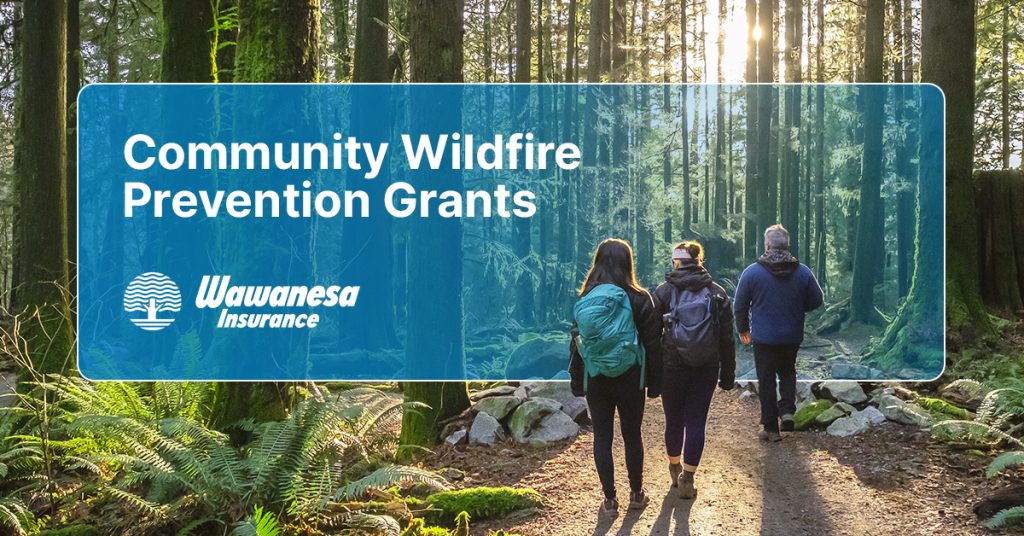 An image of three hikers hiking in a wooded forest, with a logo to the left of them with the text 'Community Wildfire Prevention Grants; Wawanesa Insurance'.