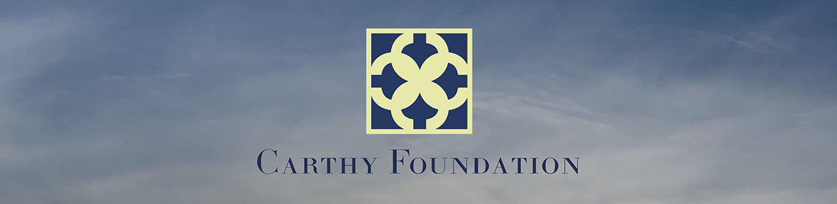 The Carthy Foundation logo over a background of a dark blue sky with clouds.