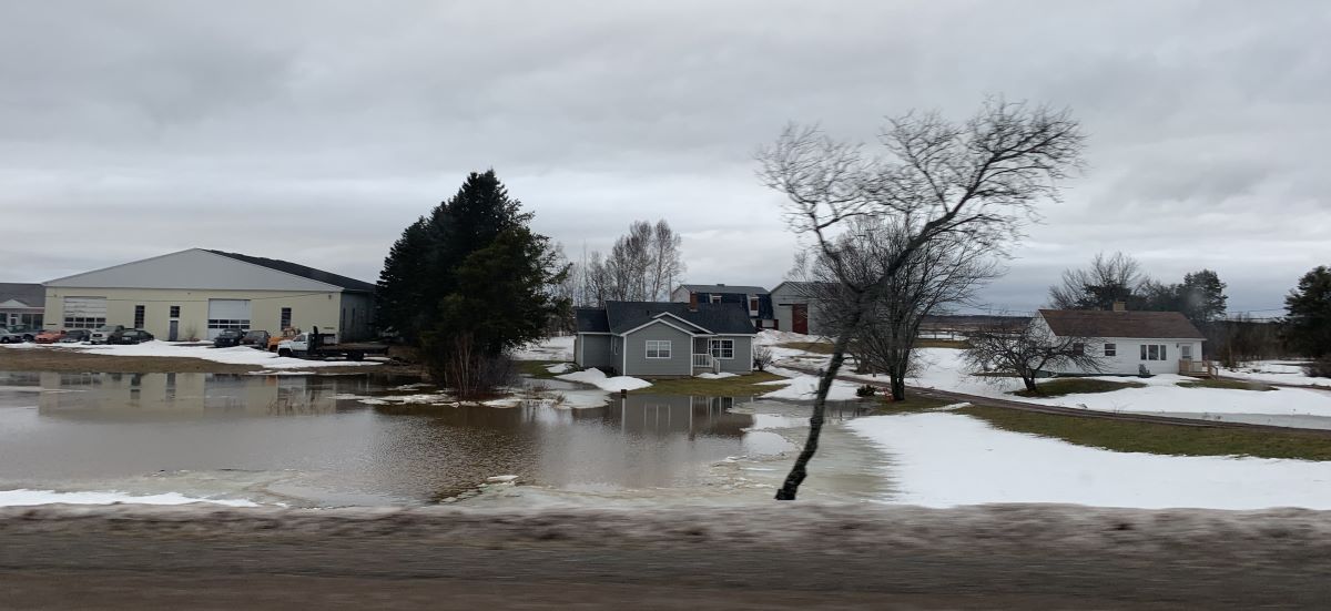 A residential area with flooding and patches of melting snow.