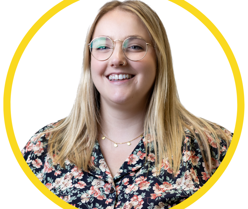 Le français suit A picture of a person with long blonde hair wearing glasses and a floral top smiling at the camera, framed by a yellow circle. Une photo d'une personne aux longs cheveux blonds, portant des lunettes et un haut fleuri, souriant à l'appareil photo, encadrée d'un cercle jaune.