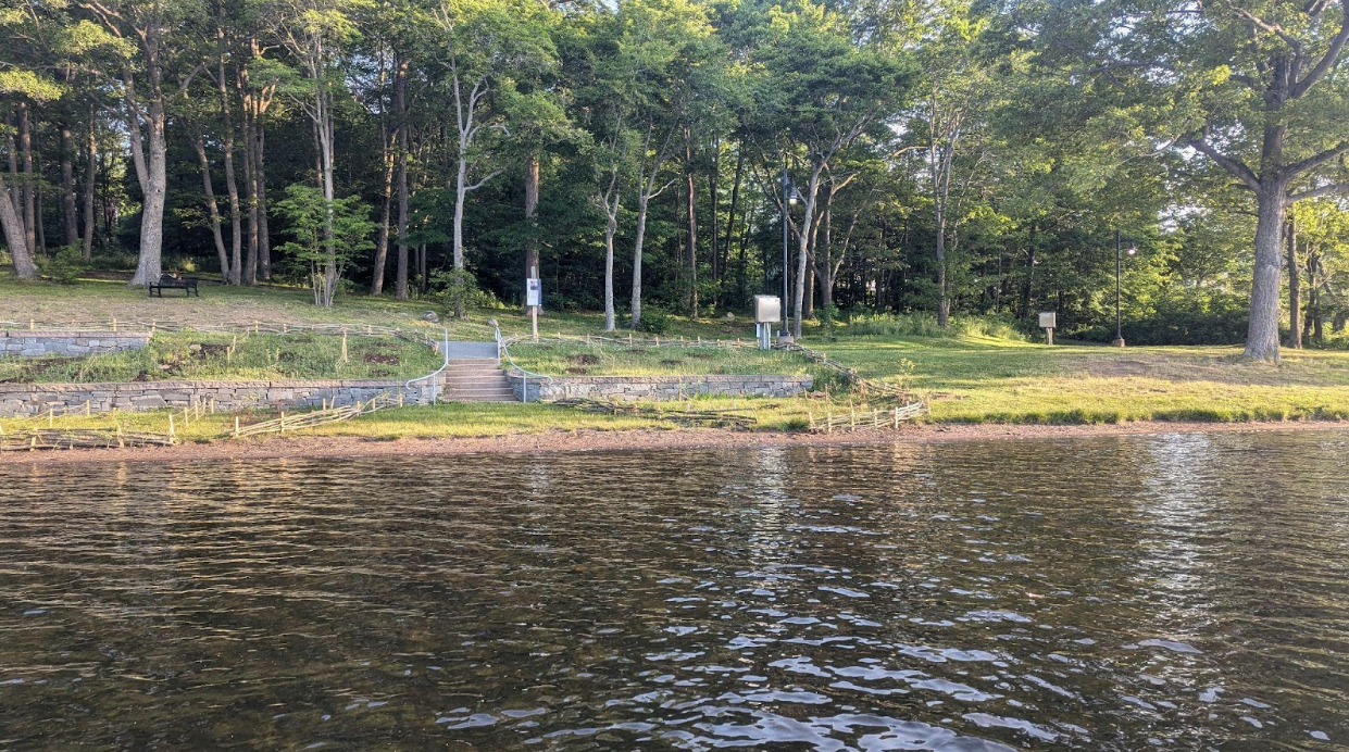 Le français suit. A view of the waterfront of Birch Cove beach in Nova Scotia. Sections of shoreline are roped off where work to restore native plants has been taking place. Vue du front de mer de la plage Birch Cove en Nouvelle-Écosse. Certaines sections du littoral sont délimitées par des cordes, car des travaux de restauration des plantes indigènes y sont en cours.