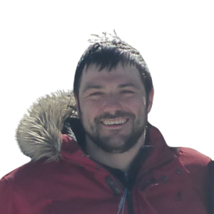 Le français suit.<br />
A picture of a person with short brown hair wearing a red winter coat smiling at the camera, framed by an orange circle.<br />
Photo d'une personne aux cheveux bruns courts portant un manteau d'hiver rouge et souriant à l'appareil photo, encadrée d'un cercle orange.