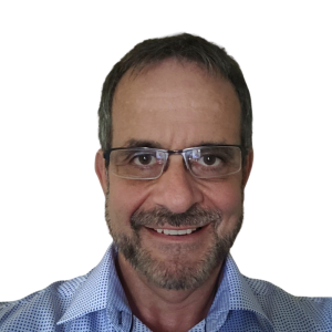 Le français suit. A picture of a person with short brown hair wearing glasses and a blue top smiling at the camera, framed by a yellow circle.<br />
Photo d'une personne aux cheveux bruns courts, portant des lunettes et un haut bleu, souriant à l'appareil photo, encadrée d'un cercle jaune.