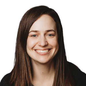 Le français suit.<br />
A picture of a person with long brown hair wearing a dark shirt smiling at the camera, framed by an orange circle.<br />
Photo d'une personne aux longs cheveux bruns, vêtue d'une chemise sombre, souriant à l'appareil photo, encadrée d'un cercle orange.